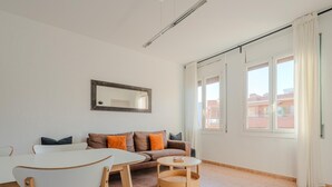Moderni olohuone, jossa on sohva, nojatuoleja, sohvapöytä ja suuri ikkuna, jossa on verhot.