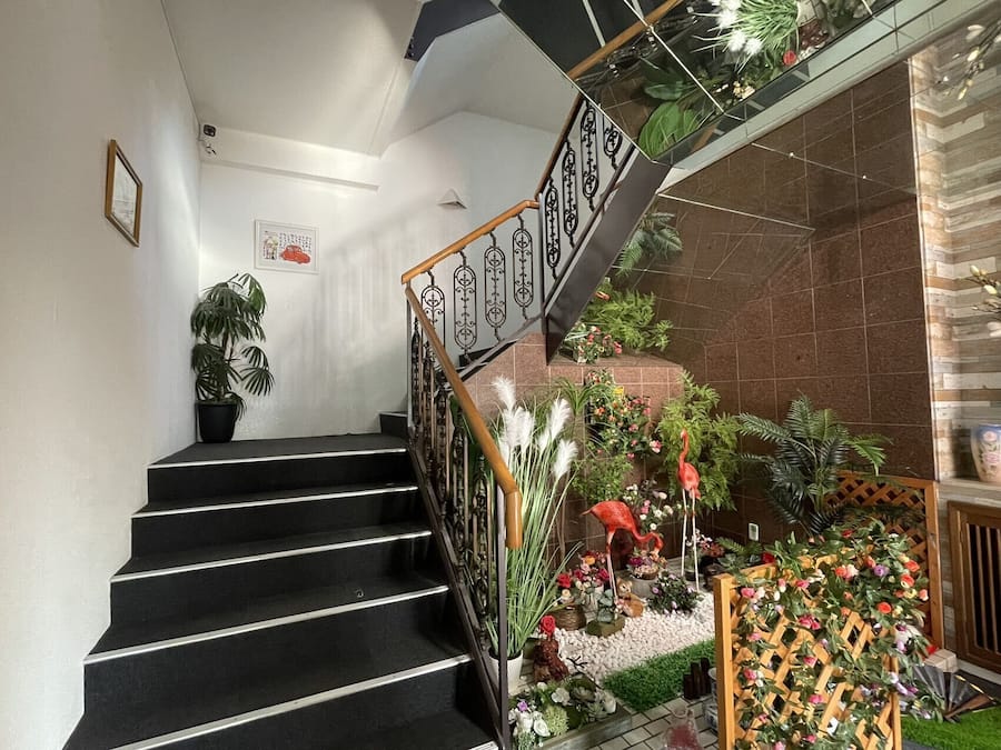 A staircase with black steps, a wooden handrail, and a black railing with decorative patterns.
