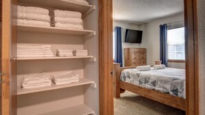 A bedroom with a bed, a TV mounted on the wall, and a wooden dresser. - Spacious 5 BDR 3 BA House with Hot Tub, BBQ, Fire Pit, Home Gym, Mountain View (Colorado Springs)