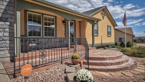 A house with a stone facade, a porch with a black railing, and a flagpole with an American flag. - Spacious 5 BDR 3 BA House with Hot Tub, BBQ, Fire Pit, Home Gym, Mountain View (Colorado Springs)