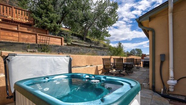 A hot tub in an outdoor patio area with a wooden deck and outdoor furniture. - Spacious 5 BDR 3 BA House with Hot Tub, BBQ, Fire Pit, Home Gym, Mountain View (Colorado Springs)