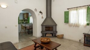 Una sala de estar con chimenea, una mesa de comedor y una cocina visible a través de un arco.