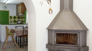 Una cocina con estufa de leña integrada, una mesa de comedor con sillas y una puerta verde.