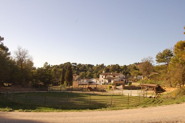 A rural property with a fenced pasture, a stable, and a large house with a tiled roof.