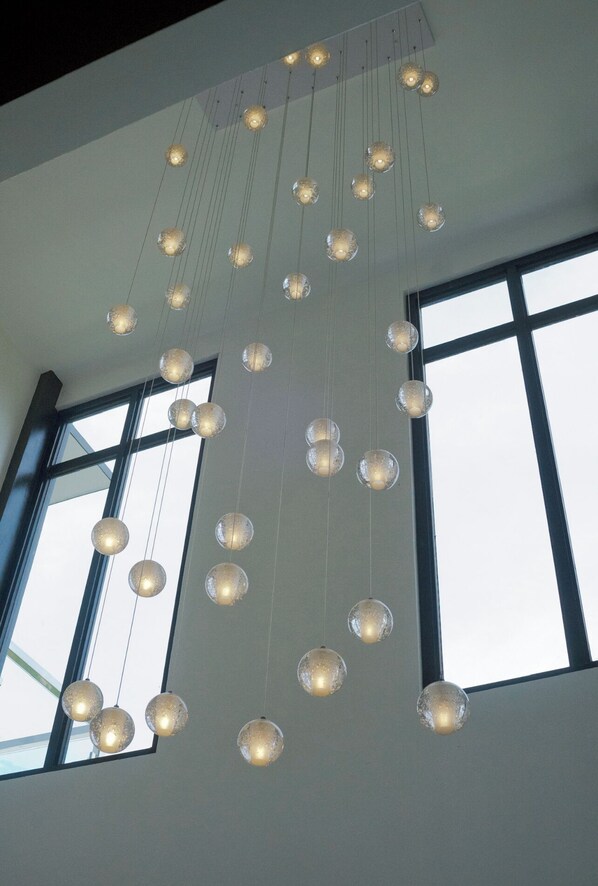A modern interior with multiple hanging spherical light fixtures and large windows.