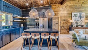 Una cocina moderna con una isla central, taburetes de bar e iluminación colgante.