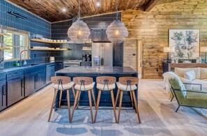 Una cocina moderna con una isla central, taburetes de bar e iluminación colgante.