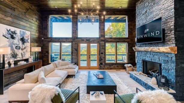 Amplia sala de estar con chimenea, ventanas grandes y una lámpara moderna.