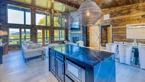 Una cocina amplia con una isla grande, techo de madera y ventanas grandes.