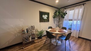 Un espace repas comprenant une table ronde, des chaises, une machine à café, une plante et un panneau fixé au mur.