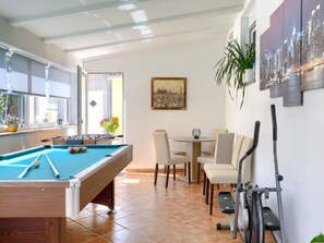Une table de billard dans une pièce qui comprend un coin repas et du matériel d’exercice.