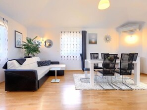 A modern living room with a sofa, dining table, chairs, and a potted plant.