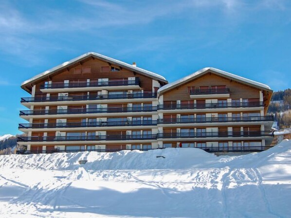 Un hotel de varios pisos con balcones, con vista a una montaña nevada.