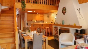 A cozy wooden cabin with a dining area, kitchen, and a loft bedroom. - Muverans I C3 by Interhome (Nendaz)