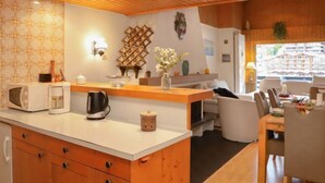A modern kitchen with a central island, wooden cabinets, and a dining area with a table and chairs. - Muverans I C3 by Interhome (Nendaz)