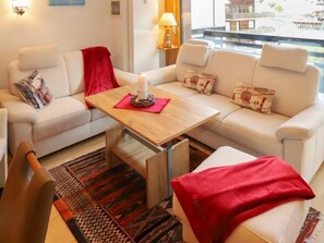 A modern living room with a sofa set, a coffee table, and a patterned rug.
