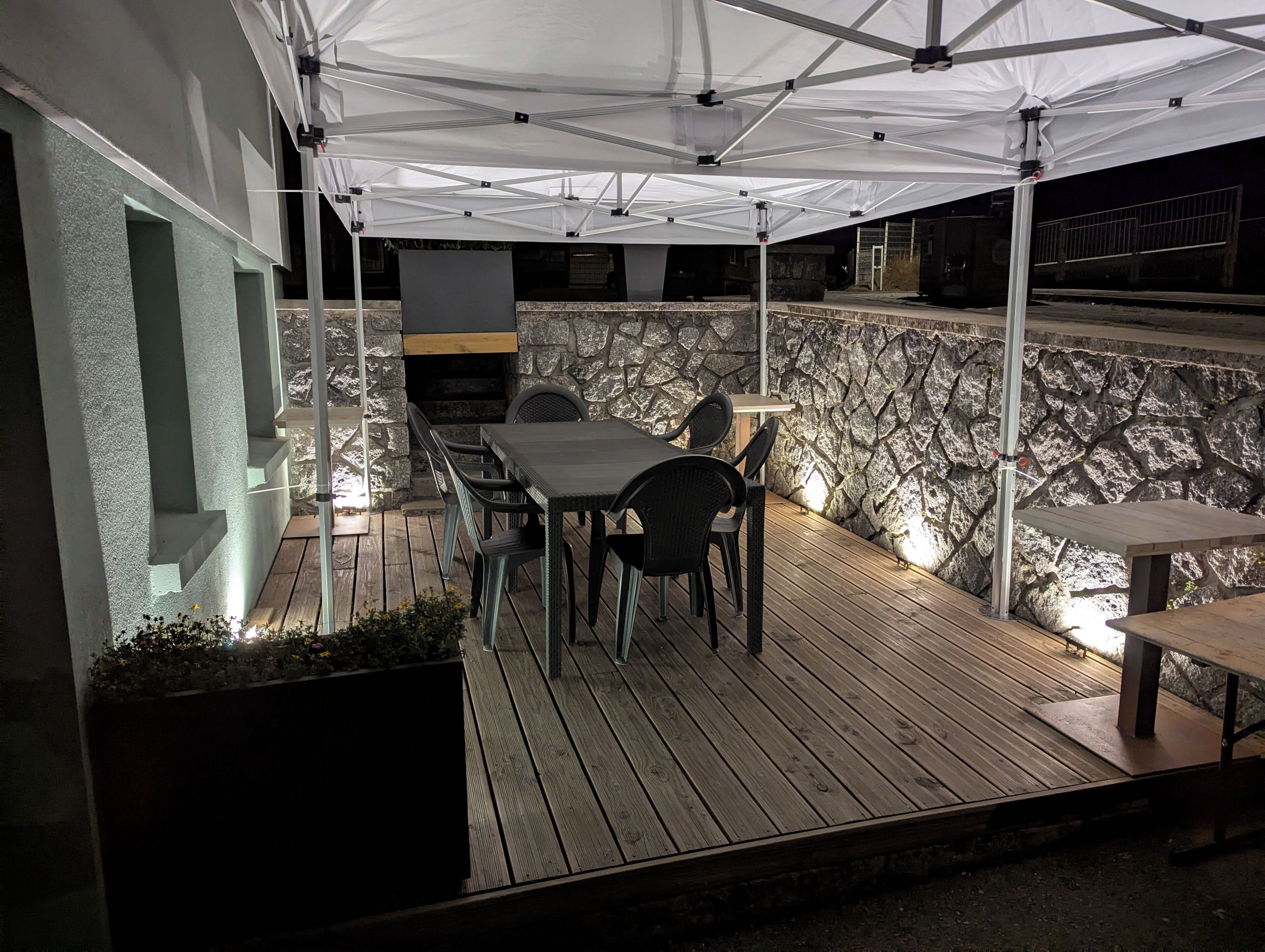 En uteplats med en stenmur, ett bord och stolar samt en grillplats.