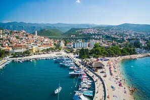 A coastal town with a marina, beach, and mountainous backdrop.