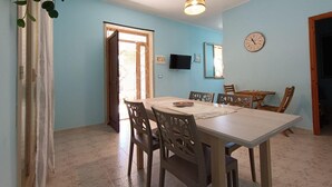 Un comedor con una mesa y sillas, un televisor montado en la pared y un reloj.