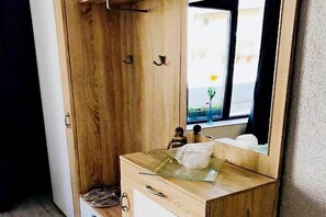 Un tocador de madera con cubierta de vidrio, una pequeña estatua y un espejo que refleja vistas al exterior.