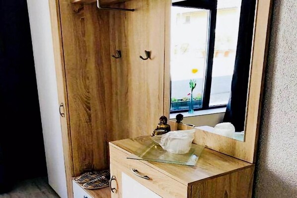 A wooden vanity with a glass top, a small statue, and a mirror reflecting a window view.