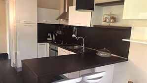 A modern kitchen with a central island, white cabinets, and a black countertop.