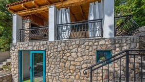 Ein Gebäude aus Stein mit einem Balkon, einer Holzpergola und einer Treppe.