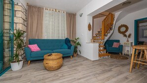 Ein Wohnzimmer mit einem blauen Sofa, einer Holztreppe und Blick ins Freie.