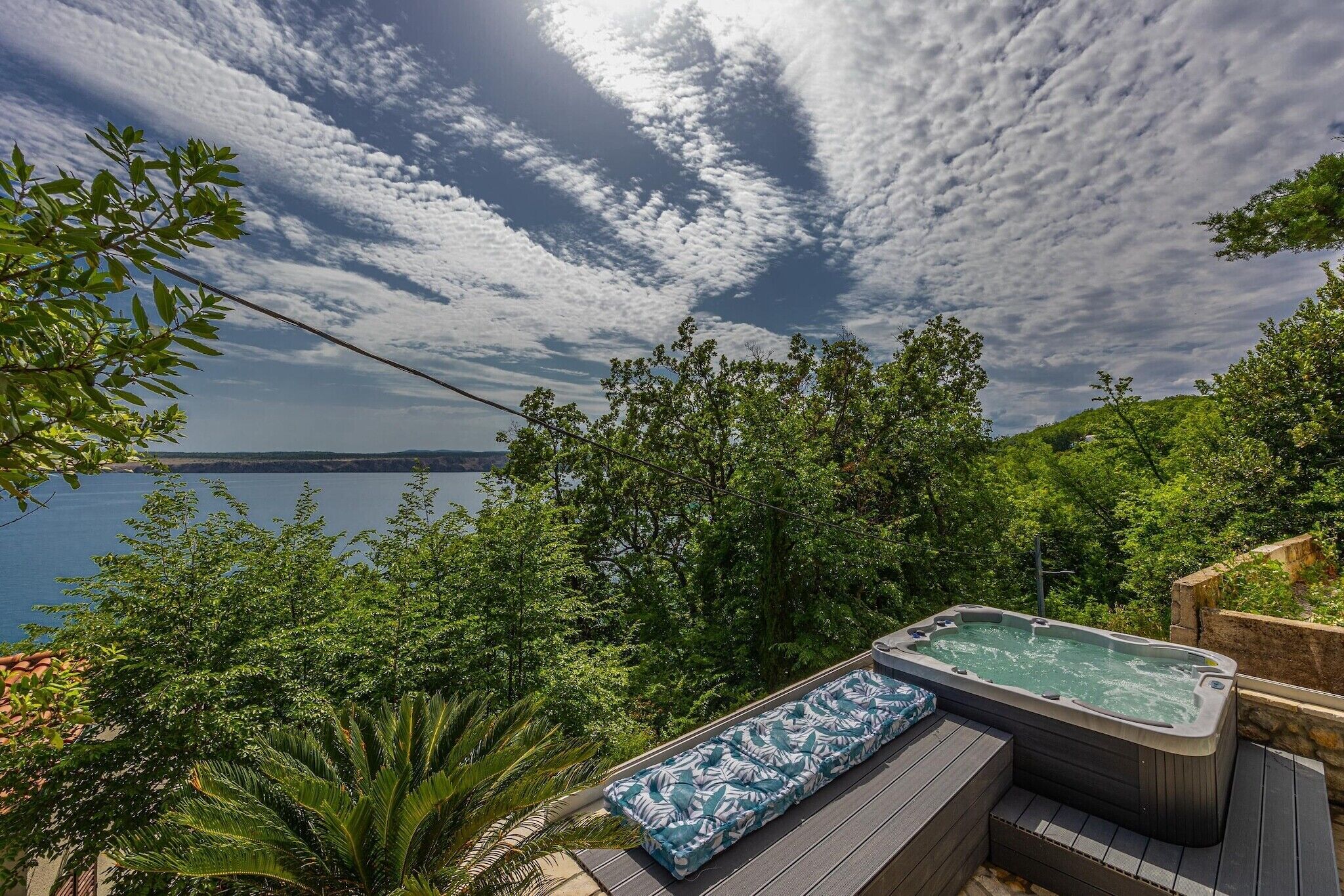 Un bain à remous sur une terrasse en bois, avec vue sur un lac et des arbres.