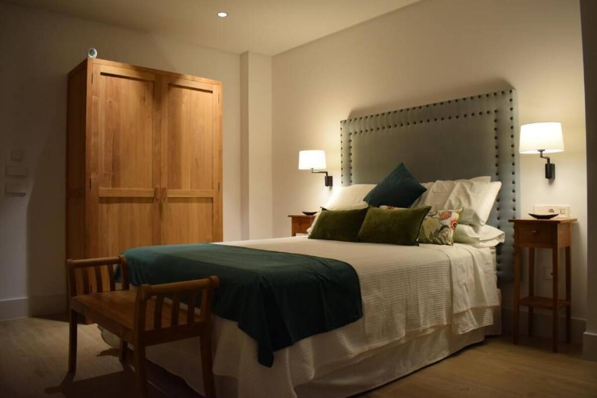Ein Schlafzimmer mit einem großen Bett, zwei Nachttischen, einem Holzschrank und einem Sessel.