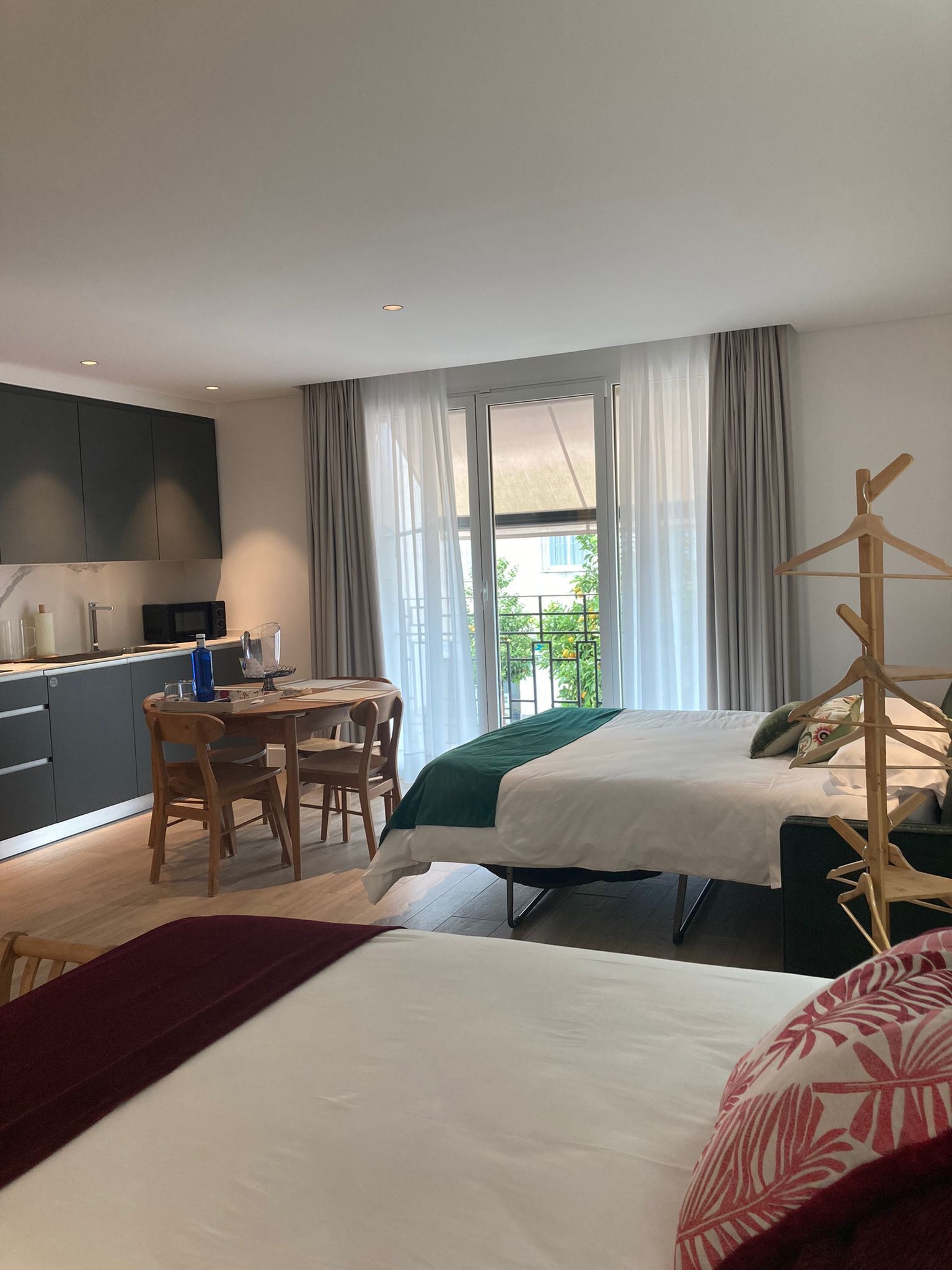 Ein modernes Schlafzimmer mit Bett, Nachttisch und Blick ins Freie.
