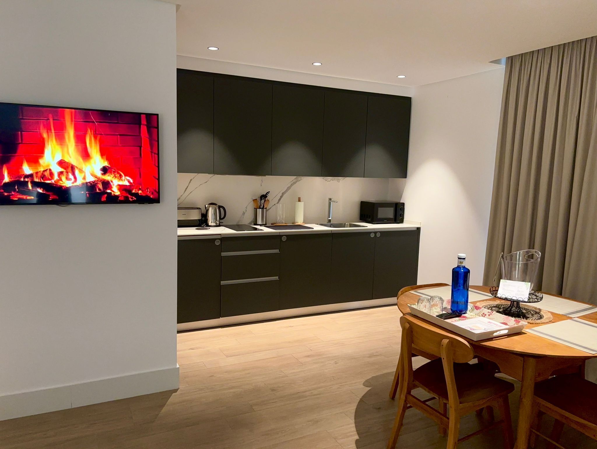A modern kitchen with dark cabinets, a microwave, and a kettle on the counter.