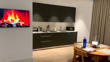 Une cuisine moderne avec des meubles de couleur sombre, un four à micro-ondes et une bouilloire posés sur le plan de travail.