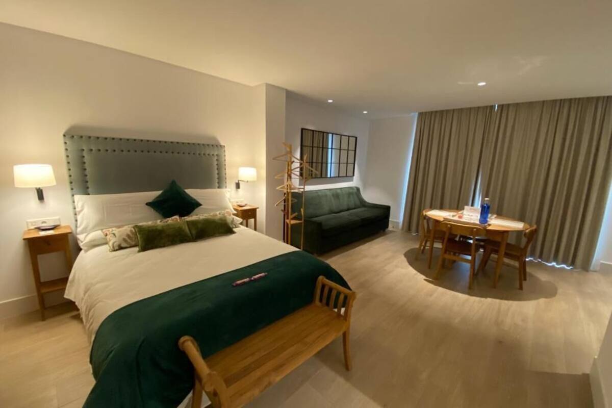 Ein Hotelzimmer mit einem großen Bett, einer kleinen Couch, einem Esstisch und einer Lampe.