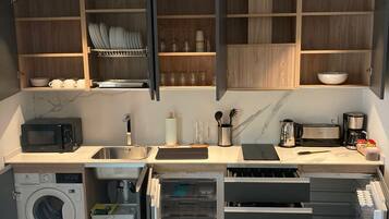 Une cuisine compacte dotée d’appareils électroménagers intégrés, de meubles en bois et d’un îlot central.
