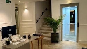 A reception area with a desk, computer, and a staircase leading to another floor. - Apartamentos Turísticos La Plaza (Chipiona)
