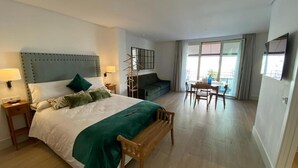 A hotel room with a bed, bedside tables, a desk, a chair, a sofa, and a balcony with a view. - Apartamentos Turísticos La Plaza (Chipiona)