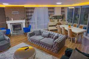 A modern living room with a fireplace, plush sofas, a dining area, and large windows. - Calm In Sapanca (Sapanca)