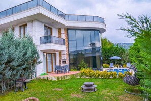 A modern two-story house with a large glass window, a balcony, and a swimming pool with lounge chairs. - Calm In Sapanca (Sapanca)