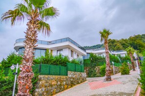 A modern building with a curved balcony, surrounded by palm trees and greenery. - Calm In Sapanca (Sapanca)