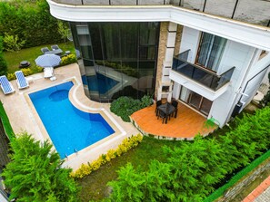 A modern house with a swimming pool, outdoor seating, and lush greenery. - Calm In Sapanca (Sapanca)