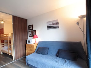 Cozy living space with a sofa, side table, microwave, and lamp.