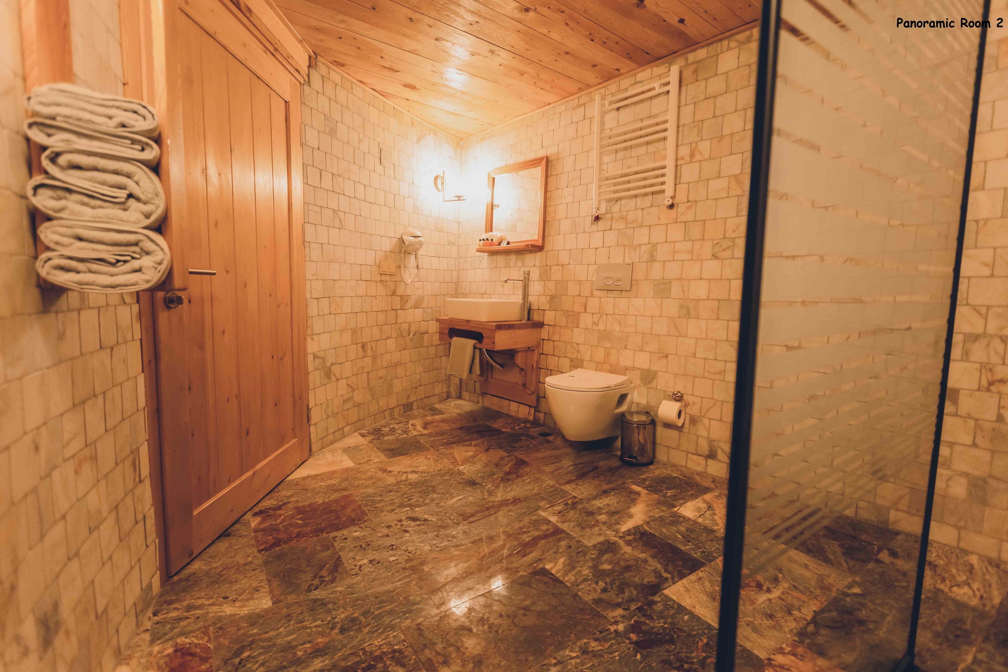 Et badeværelse med en trædør, en vask, et toilet og et spejl.