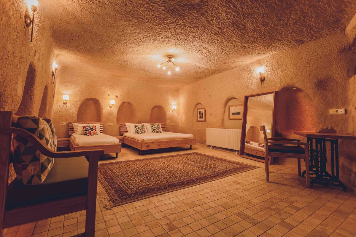 A cozy, cave-like bedroom with a bed, two chairs, a small table, and a rug.