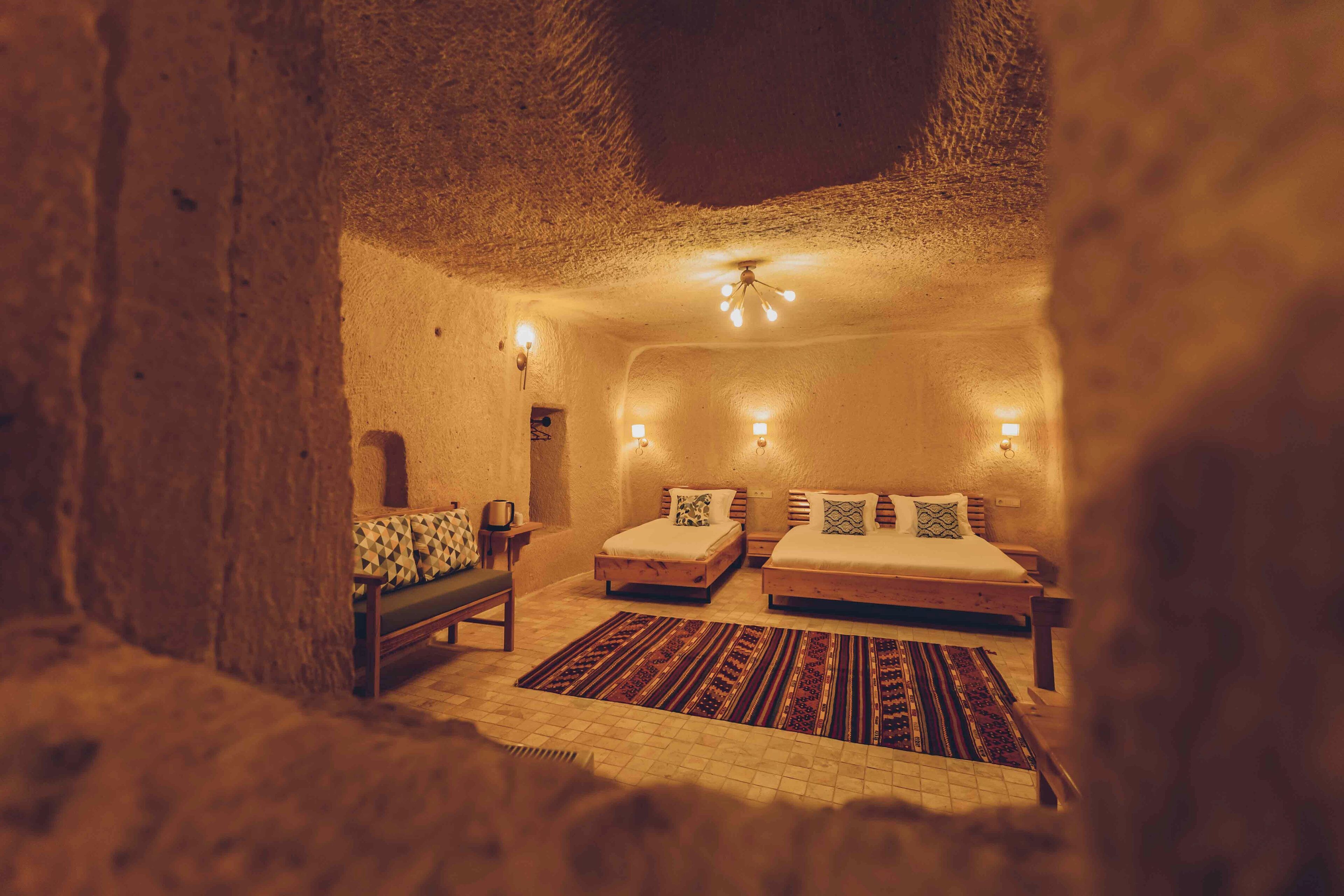 A cozy, rustic room with two beds, a bench, and a patterned rug.