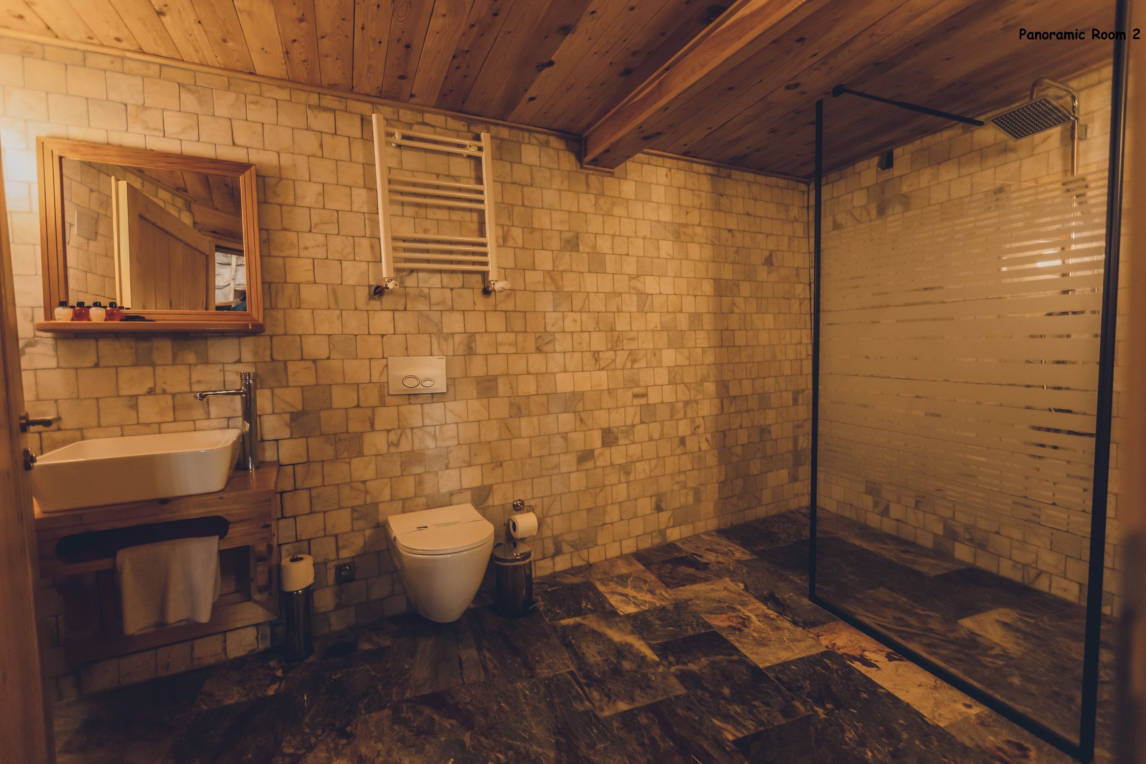 A bathroom with a wooden ceiling, a sink, a toilet, and a shower area.
