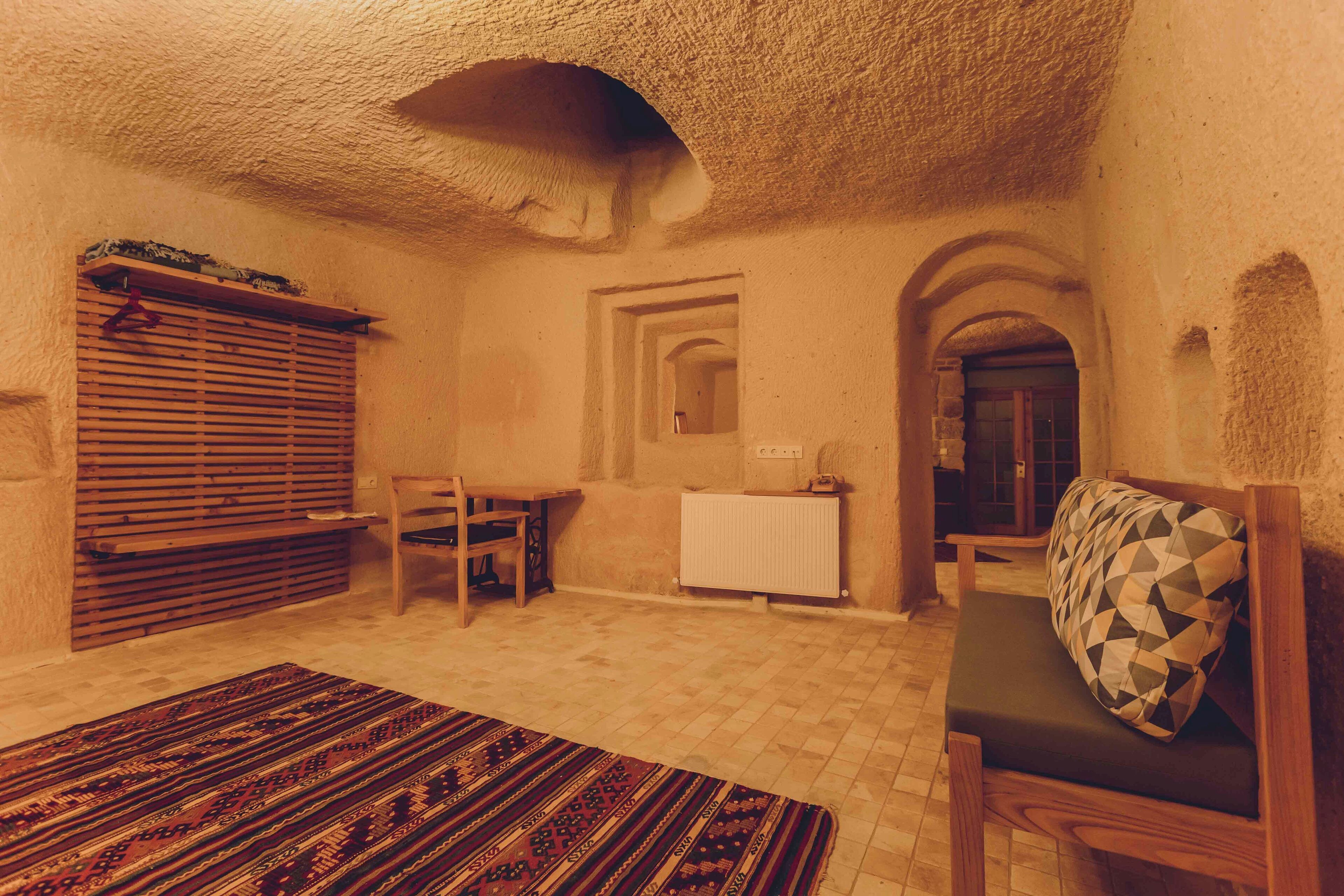 A cozy room with a wooden bench, a cushioned bench, a patterned rug, and a radiator.