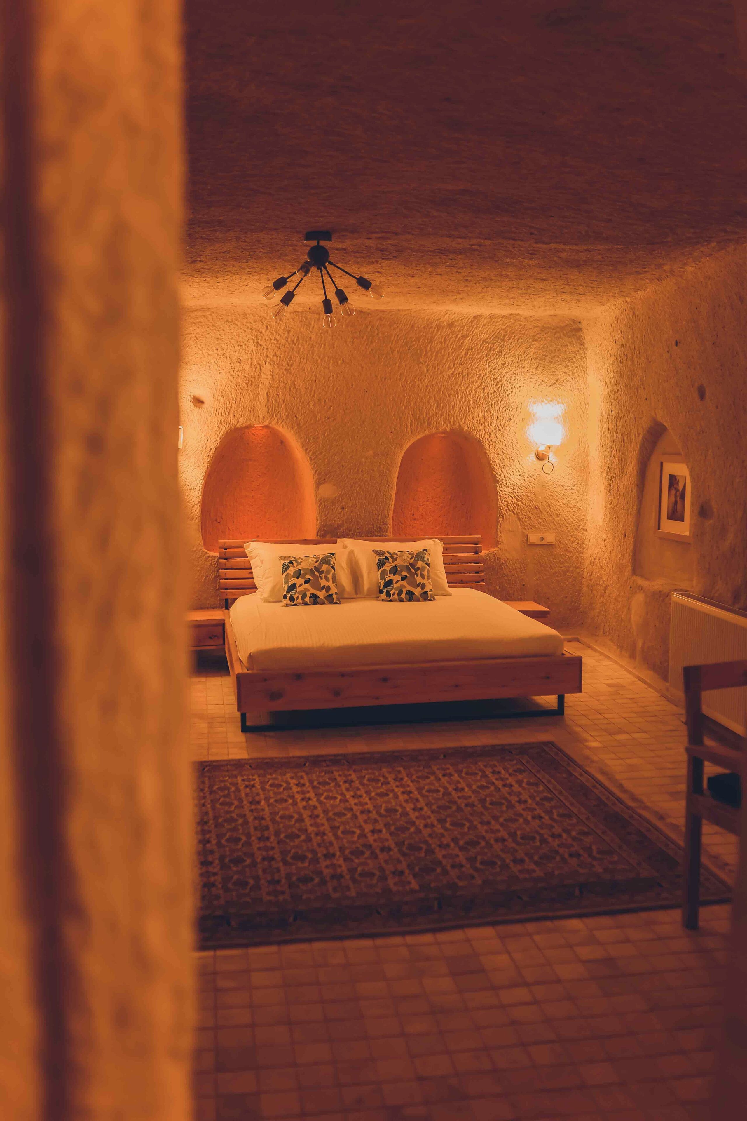 Un dormitorio acogedor con una cama, un tapete y una lámpara fijada a la pared.