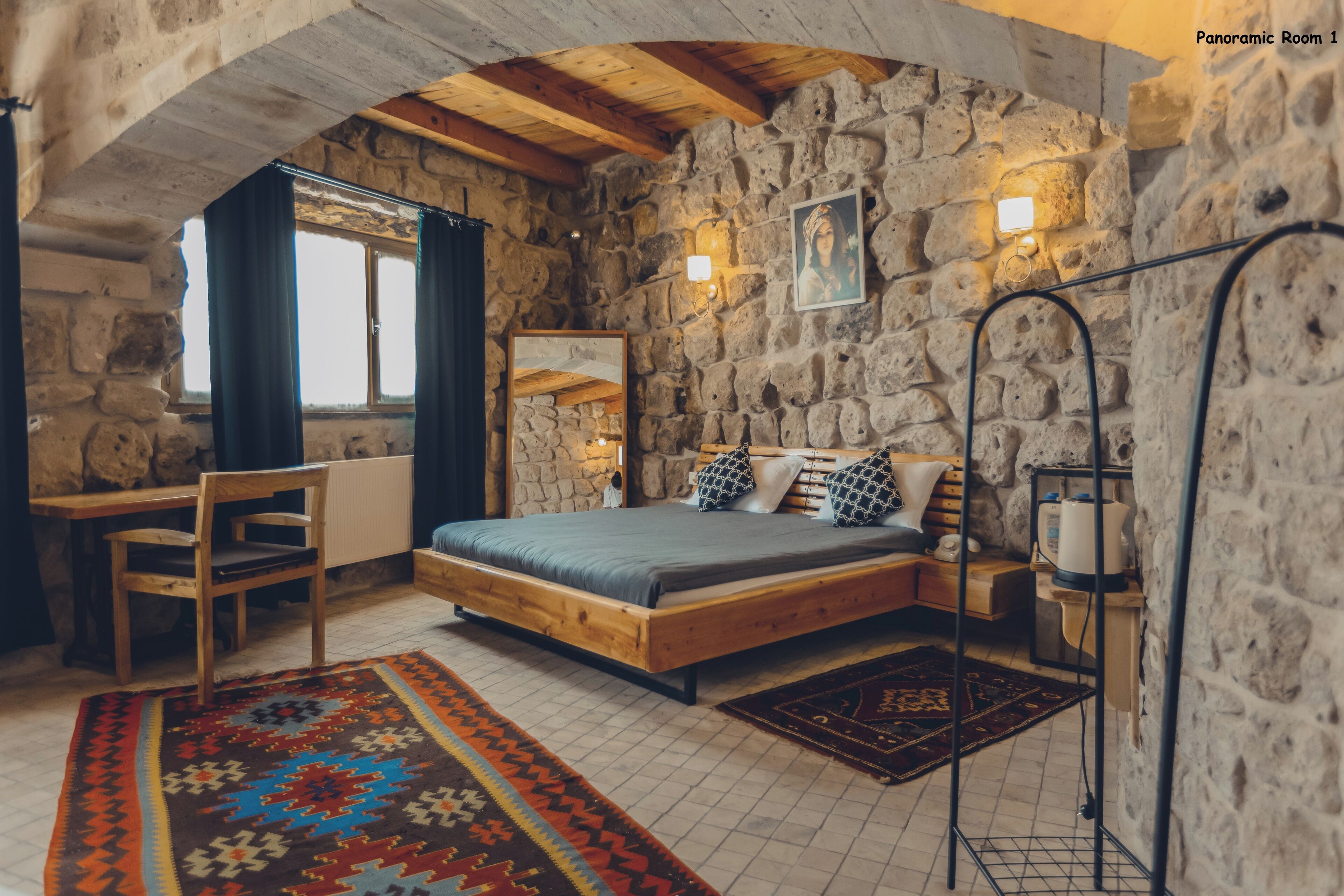 A stone-walled room with a bed, a desk, and a chair.
