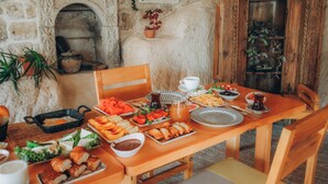 Ein Holztisch ist reichhaltig mit verschiedenen Speisen gedeckt, darunter Salate, Früchte und Gebäck.